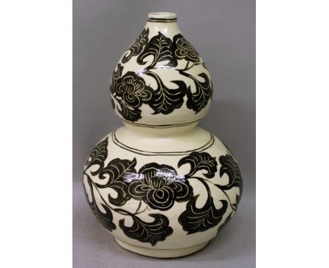 A CHINESE CIZHOU DOUBLE GOURD CERAMIC VASE, decorated in brown-black on a cream ground with bands of scrolling foliage, 10.6i