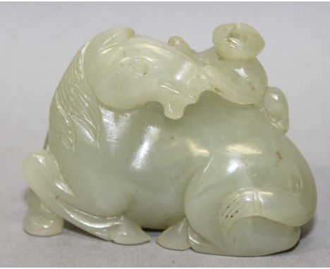 A GOOD QUALITY CHINESE CELADON JADE CARVING OF A HORSE, lying recumbent and with a monkey on its back, 2in wide & 1.5in high.