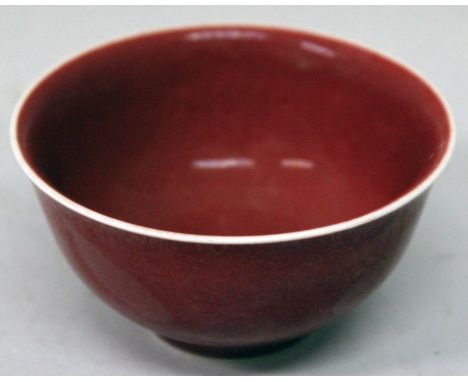 A CHINESE SANG-DE-BOEUF PORCELAIN BOWL, the sides applied with an even and slightly mottled glaze, the base with a Qianlong s