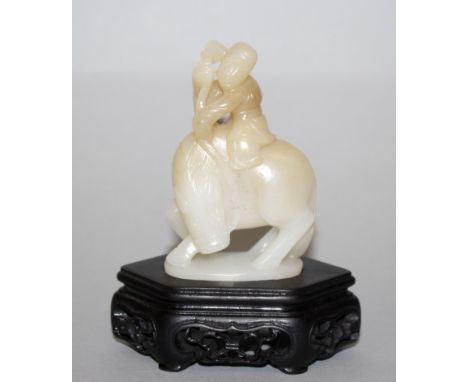 A CHINESE JADE-LIKE MODEL OF A HORSE & RIDER, the man clasping the horse's reins, together with a fitted wood stand, the mode