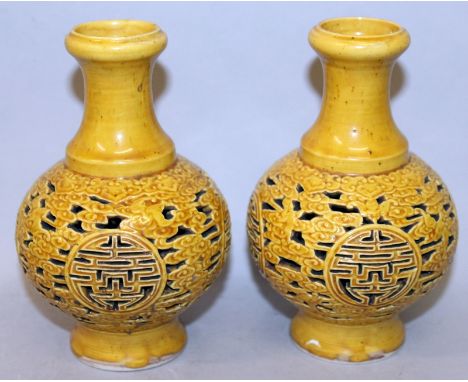 A PAIR OF CHINESE PIERCED YELLOW GLAZED VASES, each decorated with repeated Shou medallions reserved on a ground of cloud scr