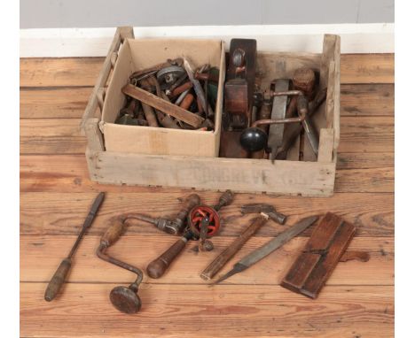 A potato crate containing an assortment of woodworking tools including planes, hammers, etc.  