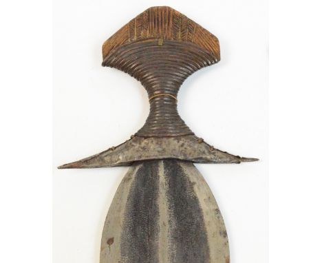 A Kuba Ikul dagger, Congo, with shaped blade, metalwork to the wooden handle and metal bound leather scabbard, length 40cm.