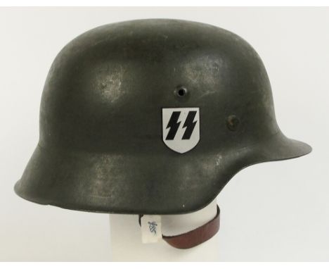 A German WWII M40 helmet with chin strap and liner and with later applied SS decal.