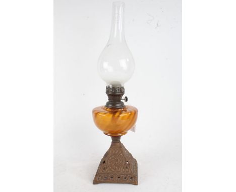 Late 19th/early 20th century oil lamp, with bulbous glass chimney and amber glass reservoir, raised on a pierced cast iron ba