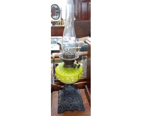 A VICTORIAN OIL LAMP with a yellow glass reservoir and a cast iron base