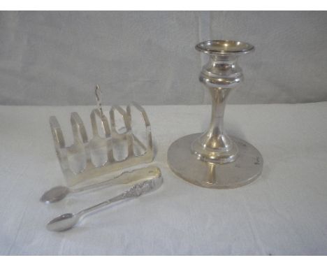 A WEIGHTED SILVER SQUAT CANDLESTICK, a toast rack and tongs
