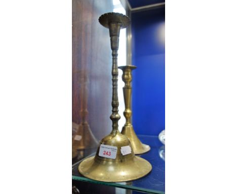 AN 18TH CENTURY BRASS CANDLESTICK with a "bell" shaped base and another similar (2)