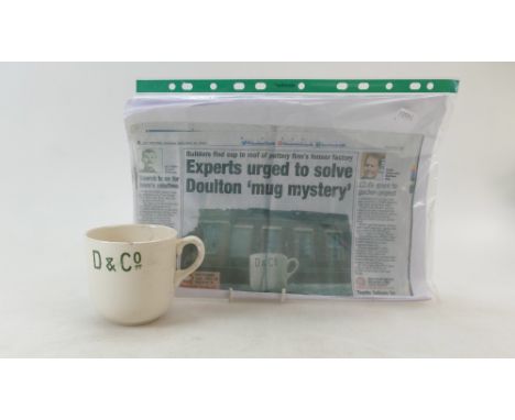 A earthenware cup decorated with D & Co, (handle broken off and chip to the rim) this cup was found up in the roof of the Nil