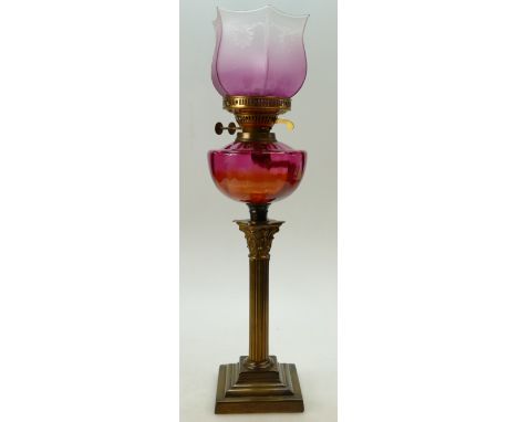 Early 20th century Corinthian column brass oil lamp with cranberry glass reservoir and shade. Overall height 69cm including c