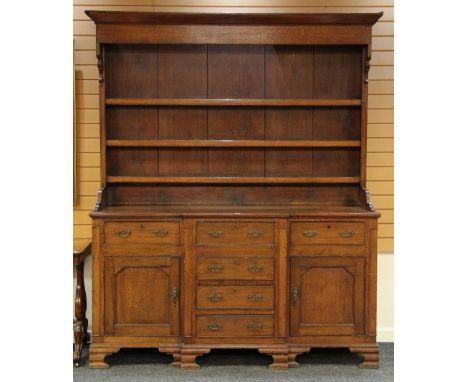 NORTH WALES BREAK FRONT OAK WELSH DRESSER having a base of four centre drawers, pair of flanking drawers over flanking cupboa