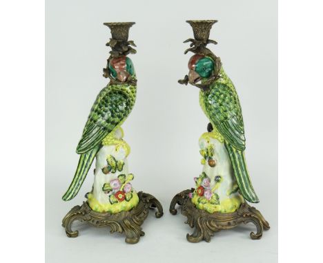PAIR OF CONTINENTAL CERAMIC &amp; GILT METAL CANDLESTICKS in the form of exotic birds holding branch in their beaks, 37cms ta