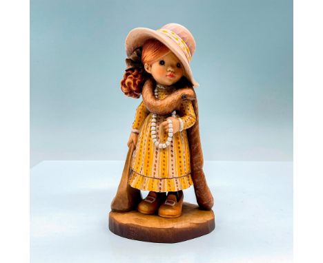 Sweet painted figure of a young girl dressed up in a yellow dress, hat, and scarf. In hues of earthy orange, yellow, tan and 