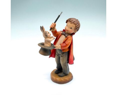 Wood carving of a little magician pulling a rabbit out of his top hat. A hand painted item with carved details to depict life