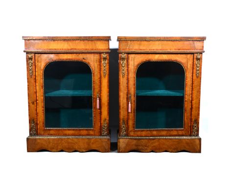 Pair of Victorian walnut vitrines, each with rectangular top, tablet frieze, arched glazed door enclosing a shelf, shaped apr