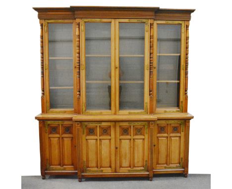 A Victorian Aesthetic Movement bleached walnut and ebonised breakfront bookcase, the moulded cornice above pair of central gl