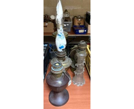 An oil lamp with clear glass base with applied glass decoration; a brass pillar oil lamp and three others **Lots must be paid