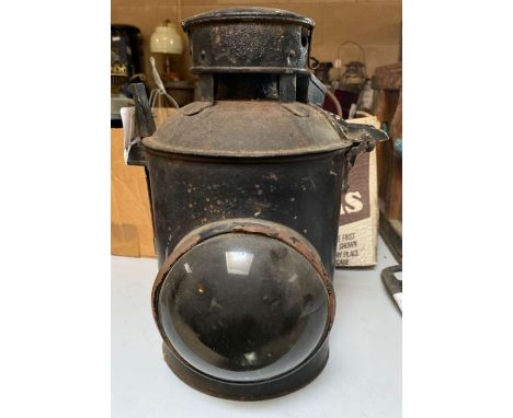 An unmarked railway lamp having black painted metal with large clear glass bulls eye lens, lacks burner (labelled "ex Longlea