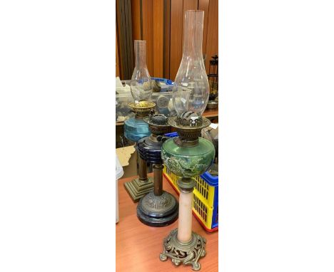 A tall Art Nouveau oil lamp with painted green glass reservoir, slender simulated onyx pillar and cast metal base, height not