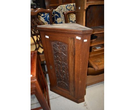 A 19th Century oak narrow corner cupboard having carved panel