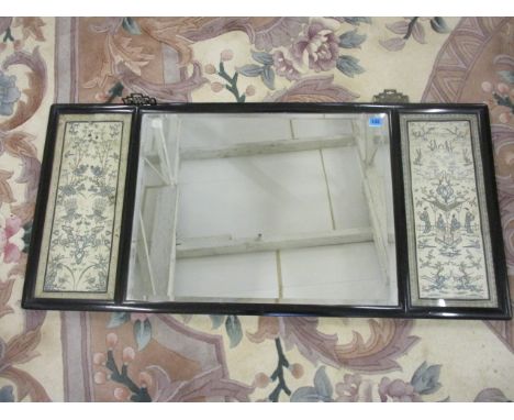 An early 20th century Chinese black lacquered mirror with a central panel flanked by a pair of tapestry panels