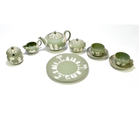 WEDGWOOD; a green jasperware three-piece tea set, together with a pair of tea cups and saucers, a circular plate and a preser