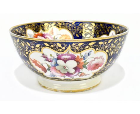 An early 19th century English hand painted porcelain bowl decorated throughout with reserves of flowers against gilt blue gro