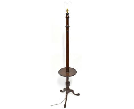 An early 20th century mahogany standard lamp/occasional table with central inset circular shelf, raised on outswept supports,