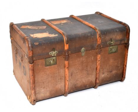 An early/mid-20th century metal bound travelling trunk with arched top and wooden slats, with various labels including London