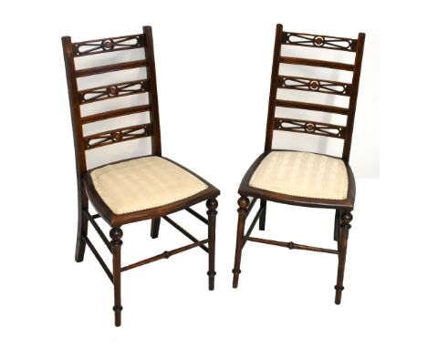 A pair of Edwardian mahogany ladder back bedroom chairs, raised on turned column supports.