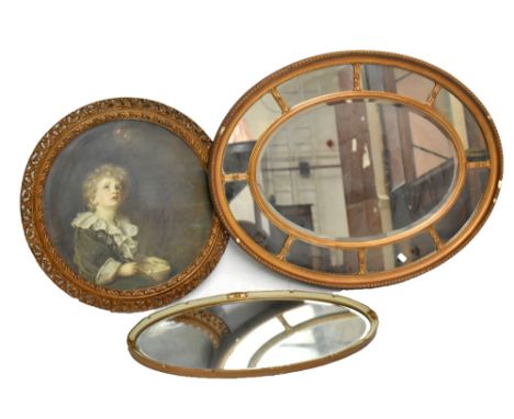 A late Victorian carved giltwood and gesso Regency style oval wall mirror, with bevelled plate, 94 x 73cm, with a smaller ova