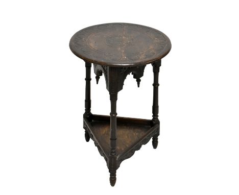 A mid-20th century carved oak cricket table, the circular top raised on triangular shaped body with carved detail raised on t