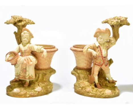 HADLEY ROYAL WORCESTER; a pair of hand painted blush ivory figural vases, modelled as a farmer boy and a girl holding a baske