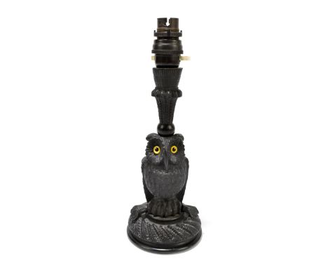 An early 20th century Black Forest figural lamp representing an owl perching on a branch, with yellow glass eyes, height incl