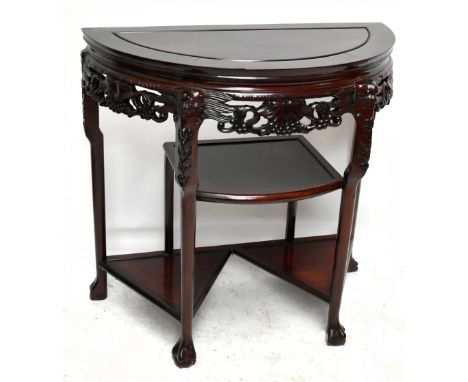 A 20th century Chinese rosewood demi-lune side table with carved skirt above three shelves, raised on ball and claw feet, wid
