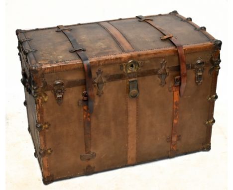 A 19th century leather and brass bound canvas travelling trunk of large proportions, with leather straps and studded detail, 