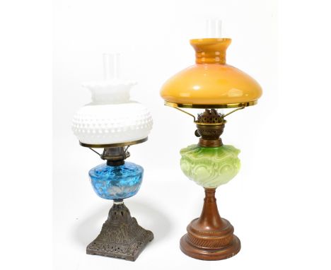 An early 20th century oil lamp, with milk glass shade with relief decoration, with blue glass reservoir with hand painted flo