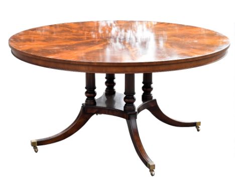 A Regency style mahogany circular dining table with radially veneered top on four turned columns and plateau with moulded out