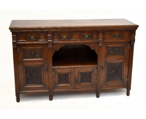 A Victorian Arts & Crafts oak sideboard with three panelled drawers and four panelled cupboard doors around a central alcove 