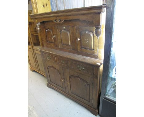 Early 20th century oak reproduction deuddarn with arched panelled doors and arrangement of three drawers on bracket feet. 