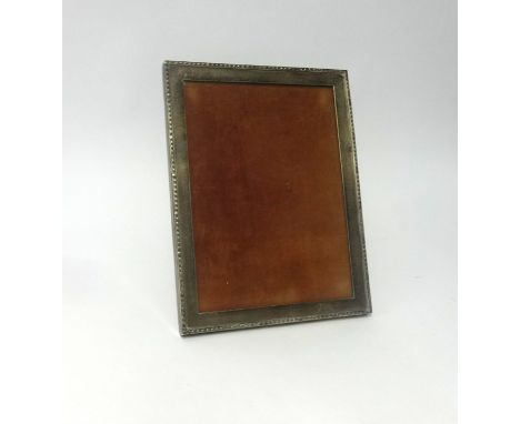 A silver rectangular photo frame, approx 24cm x 19cm with a wood easel back, indistinct hallmark.