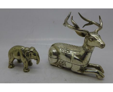 A white metal box in the form of a recumbant stag, stamped T90 and a model of an elephant, trunk a/f 