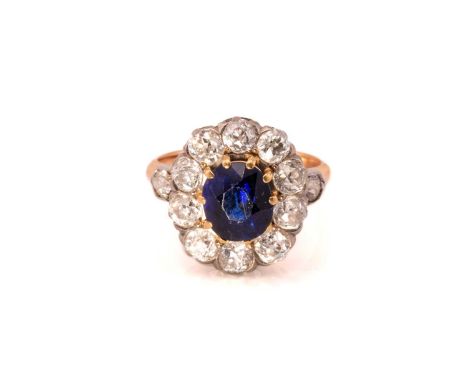 A sapphire and diamond halo ring, comprises a cushion-cut sapphire with a deep intense blue body colour, approximately measur