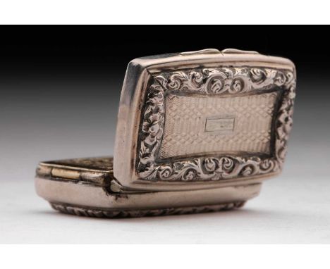 A George IV vinaigrette; rounded rectangular with applied, cast foliate border; engine-turned cover and base around a vacant 