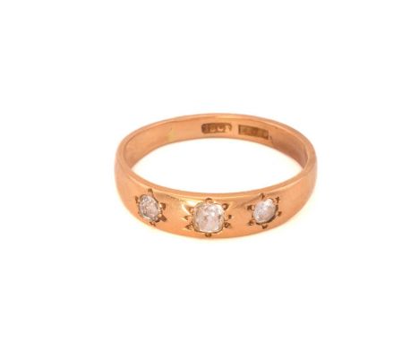 A three-stone diamond ring; the slightly graduated, mixed old-cut diamonds star set within a tapering band marked '18ct' with