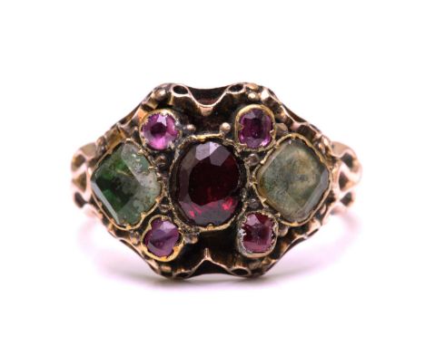 A gem-set dress ring in yellow metal, featuring an oval cut garnet in the centre flanked by two foiled-back square cut quartz
