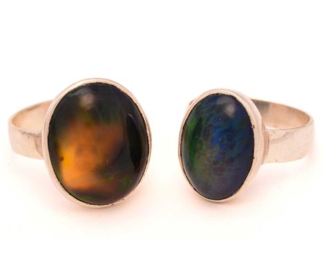 Two black opal rings; First consists of an oval Ethiopian opal cabochon, displaying play-of-colour in a digit pattern, agains