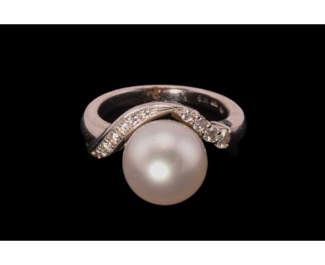 A Mikimoto pearl and diamond dress ring, comprises a 10.8 mm white pearl with a pink overtone, set on an undulating wave surr
