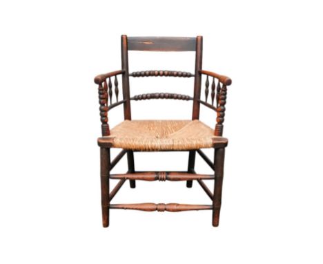 A 19th century ash Sussex style open arm chair - graduated bobbin turned rails with a rush seat.