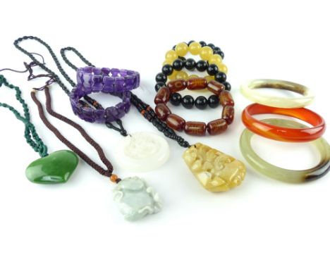 Four carved jade pendants on a string and beads, three depict Chinese symbols and one shaped as a heart, along with two ameth
